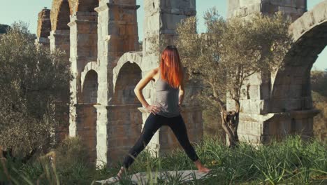 atleta femminile che esegue routine di yoga che si estende all'interno del deserto presso l'antico acquedotto