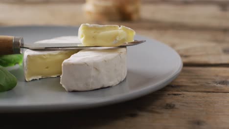 Video-close-up-of-knife-and-soft-cheese-on-plate-and-rustic-wooden-table