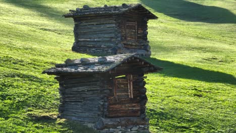 two old wooden huts on a mountain meadow in the alps