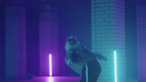 A-steel-woman-dances-hip-hop-freestyle-in-a-modern-style-in-a-hall-with-neon-light-in-purple-blue-colors.-Female-Professional-Hip-Hop-Dancer