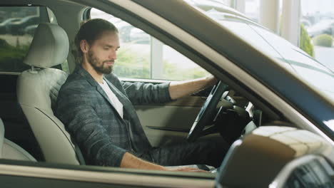 man sitting in a car in a car dealership