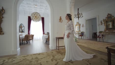 blonde bride with wedding dress walking smiling in luxurious mansion