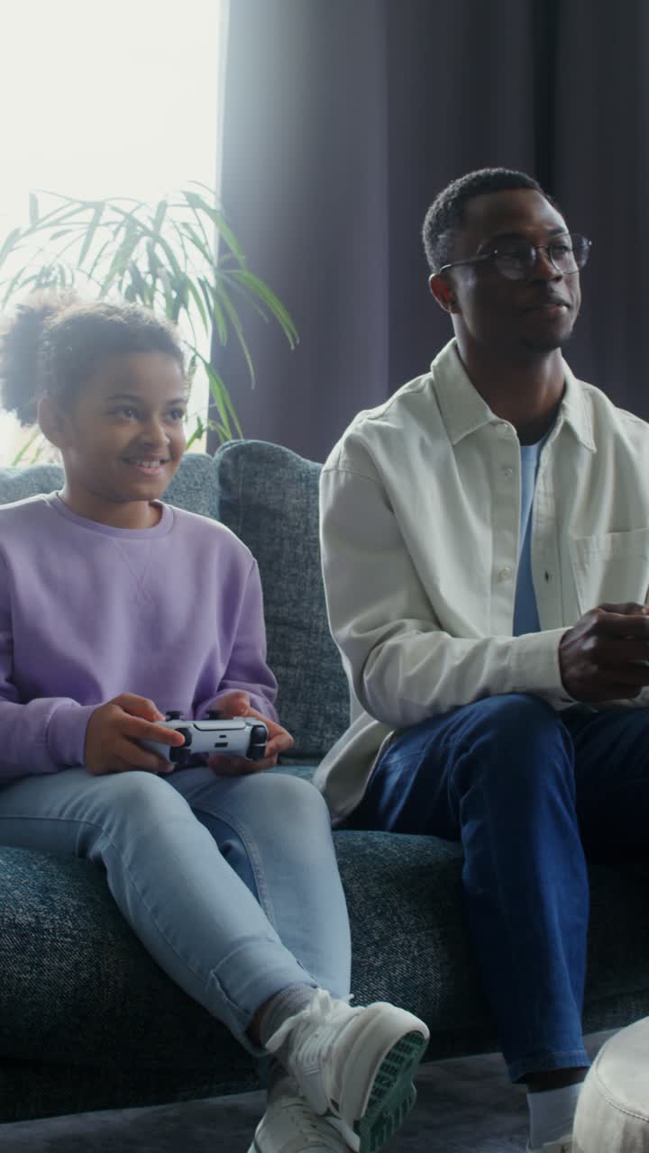Father and daughter playing video games at home