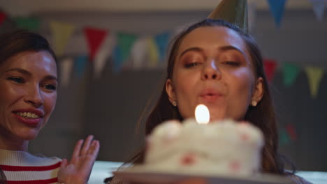 Girl enjoy birthday surprise amazed by cake close up. Happy woman blowing candle