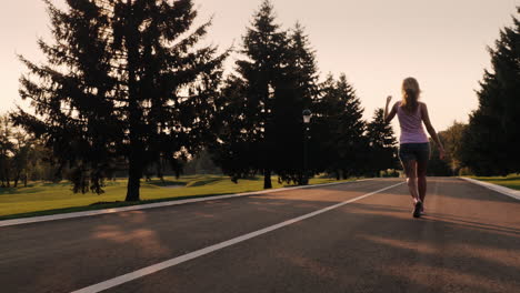 Silhouette-of-carefree-young-woman-running-on-the-lawn-at-sunset