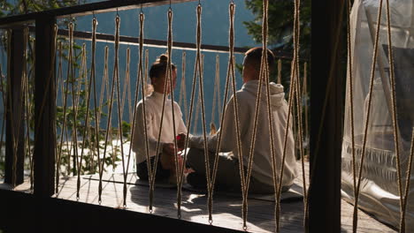 partners share meditation session on terrace sitting opposite. young man and woman engage yoga exercises nurturing mind. holistic journey of self-discovery