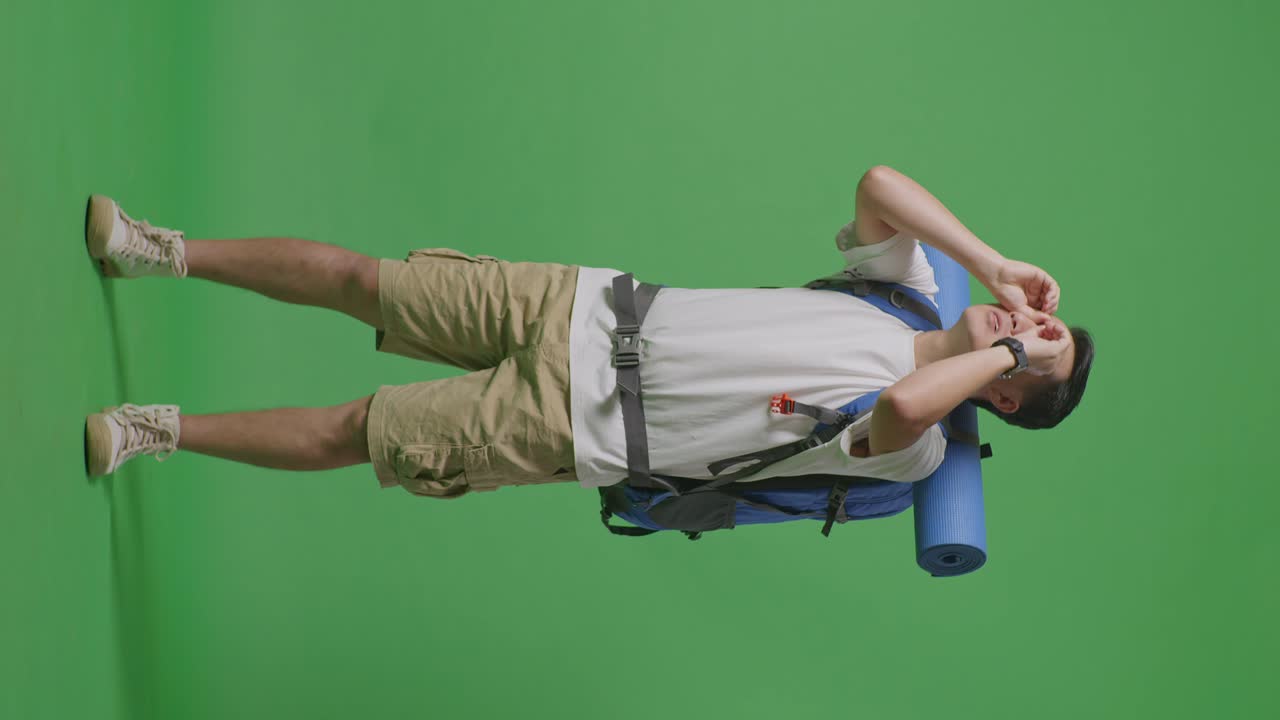 hombre con mochila cubriendo los ojos en la pantalla verde