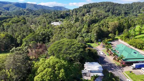 drone footage captures lush greenery and a quaint town in uki, nsw, under bright daylight, showcasing natural beauty and serene environment