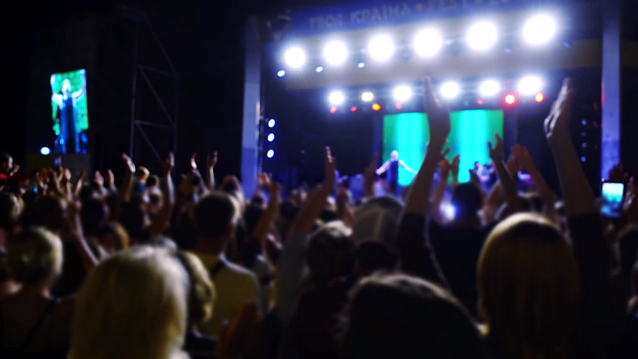 Concerto sul palco. Folla di persone e musicisti sulla scena. Fuori fuoco