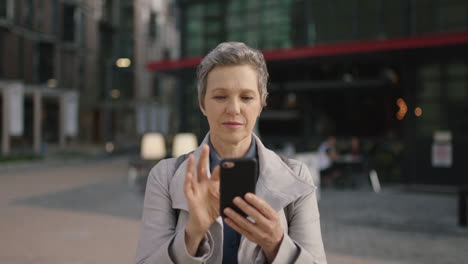 Retrato-De-Una-Mujer-De-Negocios-Profesional-Madura-Esperando-En-La-Ciudad-Navegando-Mensajes-De-Texto-Usando-Tecnología-Móvil-De-Teléfono-Inteligente-En-La-Ciudad