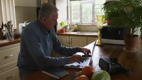 hombre mayor usando computadora portátil y teléfono móvil en casa