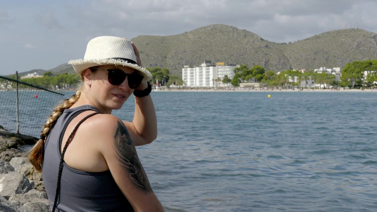 A woman in a hat looks out to sea