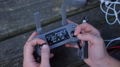 disparo de ángulo alto del piloto del avión no tripulado usando el controlador dji, moviendo el joystick hacia arriba y hacia abajo