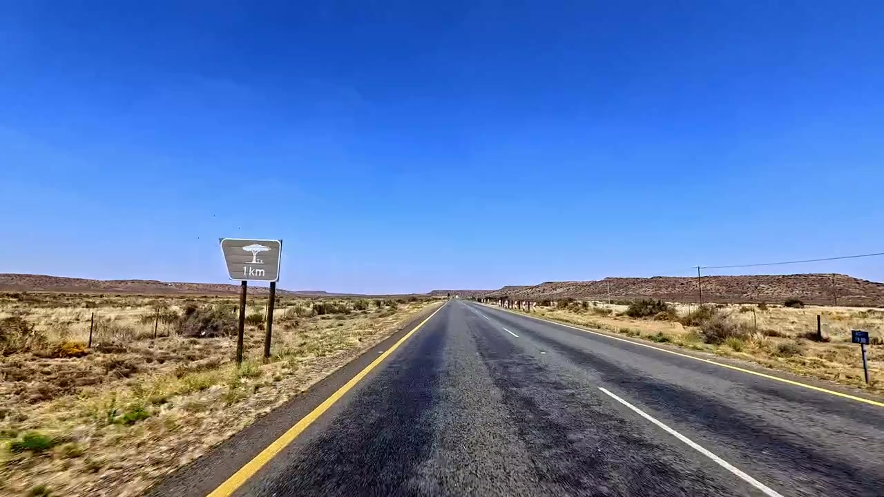 Lungo tratto di strada fiancheggiato da terreno arido e segnaletica stradale