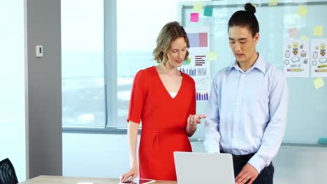 Business-colleagues-discussing-over-laptop