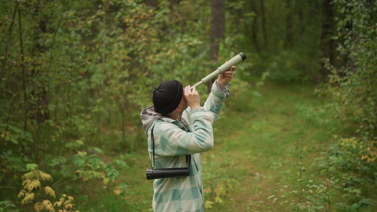 Adventurer scans woodland using instruments, Seeker inspects trees carefully with optical tools, Excursionist attentively analyzes natural environment and tree tops with specialized equipment