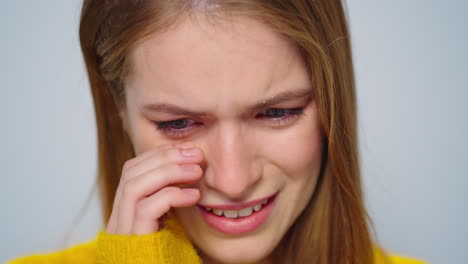 closeup attractive woman crying at camera on grey background in studio.