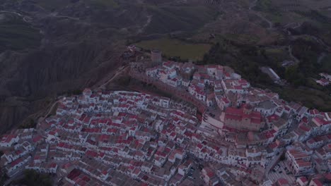 Reveal-shot-of-Historic-Pisticci-town-on-hill-top-during-sunset,-aerial