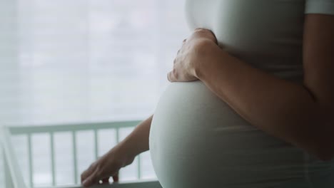 video of pregnant woman standing next to a crib.