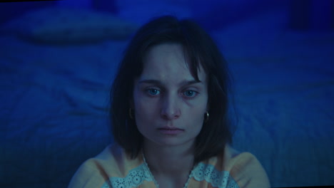 a traumatised and disoriented girl sits on the bedroom floor