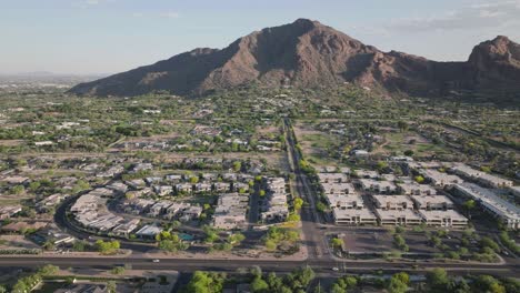 Aerial-pan-shot-of-Paradise-valley-with-E-Lincoln-DR-and-Camelback-mountain-at-background-during-summer-afternoon-in-Arizona,-USA