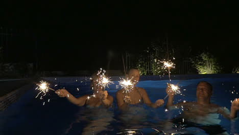 three people having fun with bengal fires in the pool