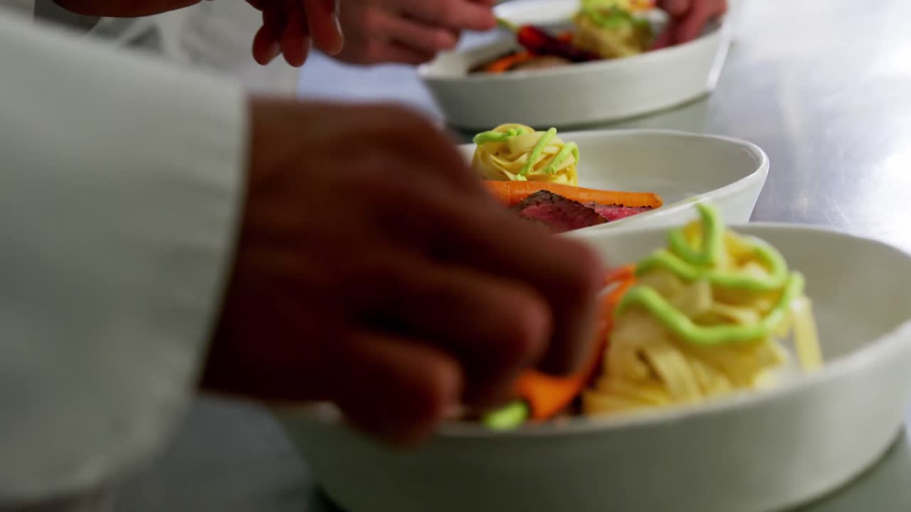 primer plano de un equipo de chefs adornando platos