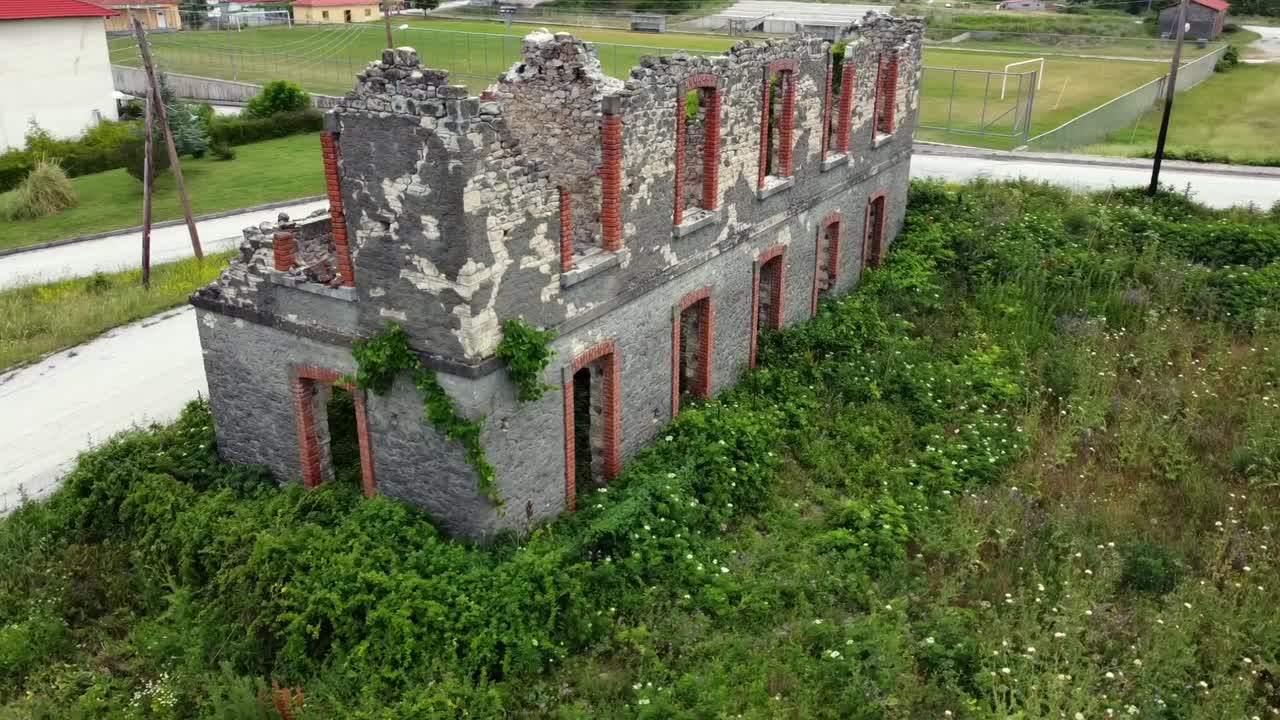 Inquadratura orbitale cinematografica con drone della stazione ferroviaria in rovina di Karpero a Grevena. Un edificio storico in pietra degli anni '30, parte della linea incompiuta Kalambaka-Kozani. Ideale per documentari di storia e di urbex.