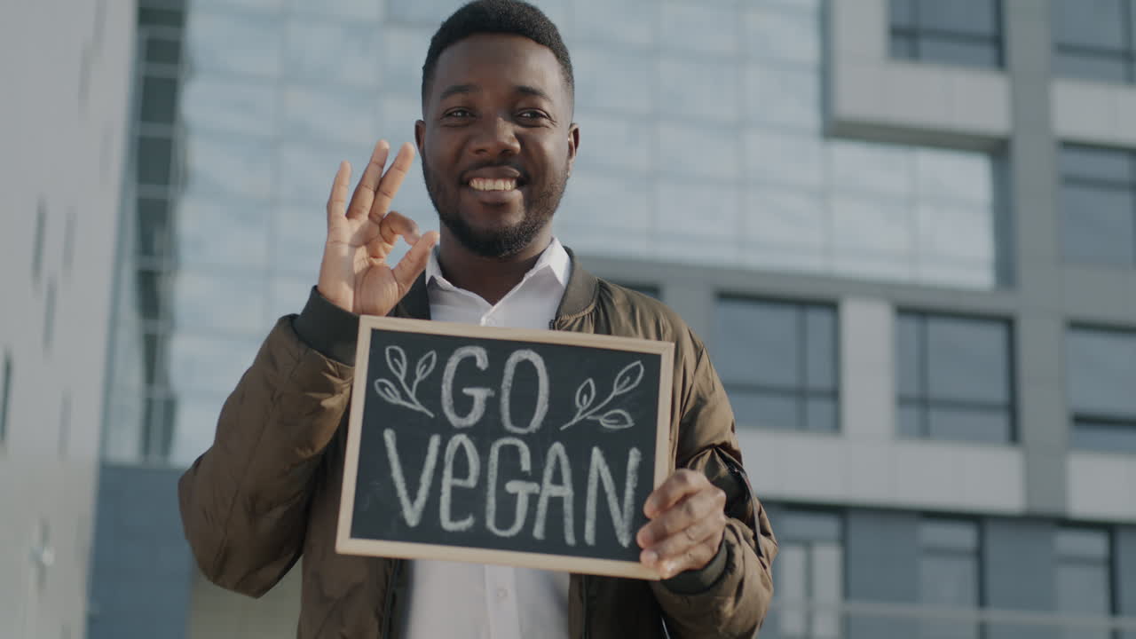 Mann hält ein "Go Vegan"-Schild