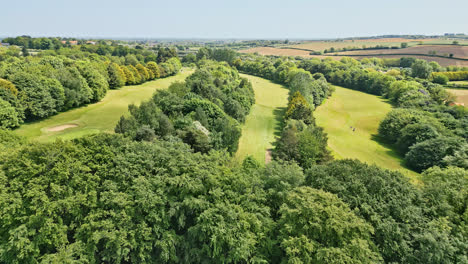 A-UK-country-park-in-summer,-showcased-via-drone-footage—people-relishing-a-winding-stream,-picturesque-picnic-spots,-and-a-wooded-attraction