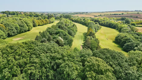 a uk country park in summer, showcased via drone footage—people relishing a winding stream, picturesque picnic spots, and a wooded attraction