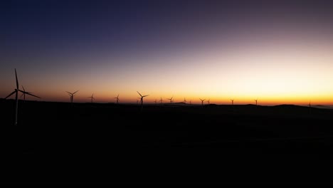 Vista-Aérea-De-Lapso-De-Tiempo-Del-Parque-Eólico-Como-Amaneceres-Sobre-El-Horizonte-Al-Amanecer,-Israel