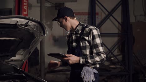 técnico de servicio de automóviles que usa una tableta digital para examinar el interior del vehículo.