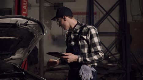 car service technician using digital tablet to examine the vehicle insides.