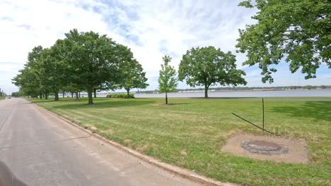 pov while slowly driving thru a green space park with the great river trail along the mississippi river in the quad cities, illinois