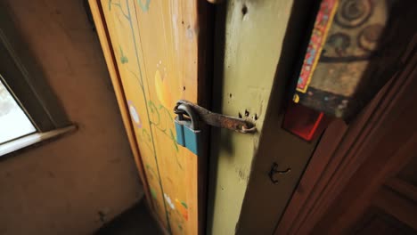 metal latch locks colorful old door inside aged rural home with folk decor style