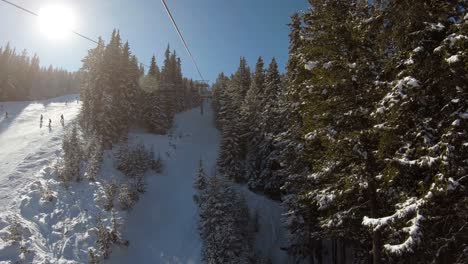 Ride-on-a-ski-lift-next-to-a-ski-track-that-goes-between-trees