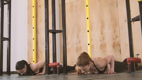 Two-Young-Athletic-Women-Doing-Abdominal-Exercises-And-Climbing-A-Wall-With-Their-Feet-In-The-Gym-1