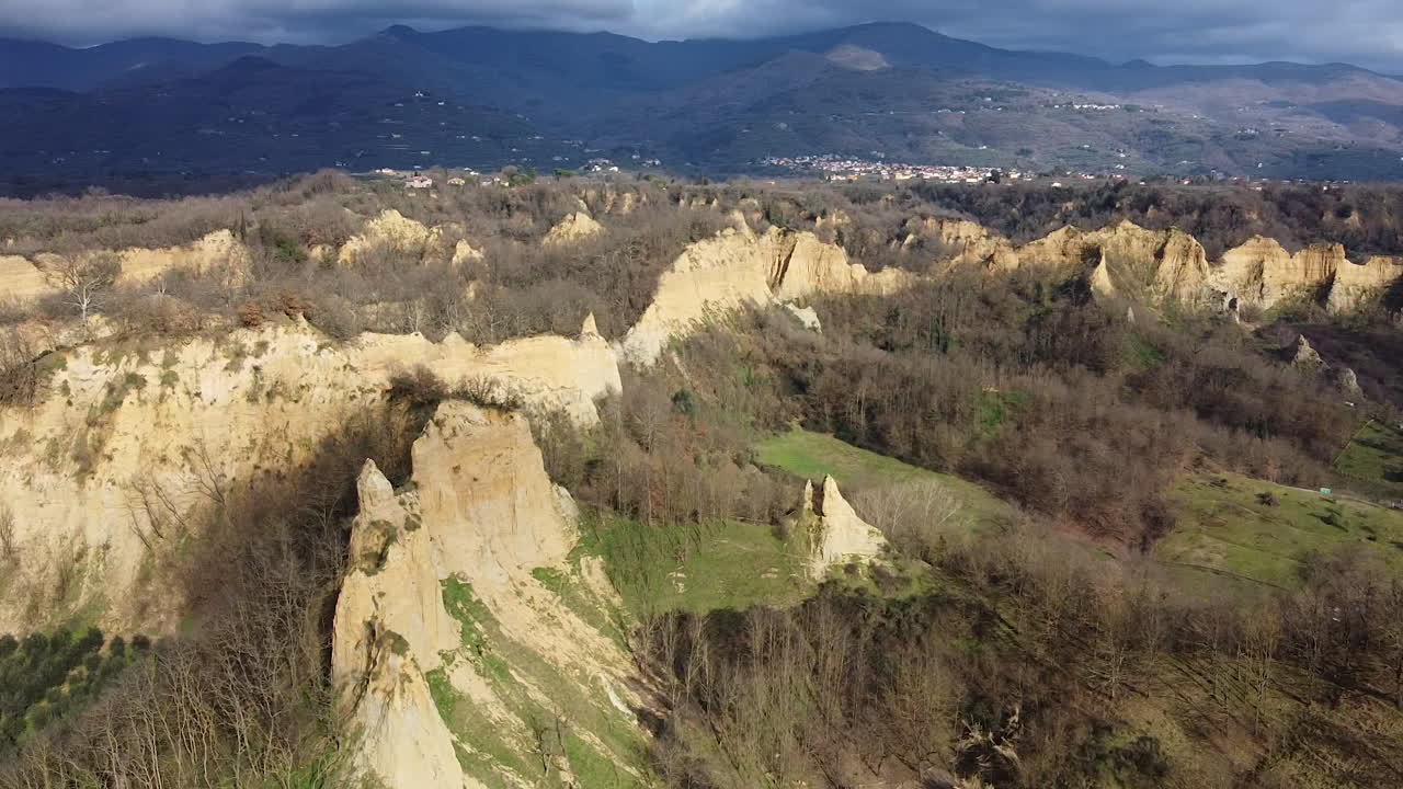 Aerial flying drone panning shot over prehistoric age canyons Le Balze natural reserve near Reggello. Tuscany, Chianti area. Italy. Winter season, partially sunny sunset.