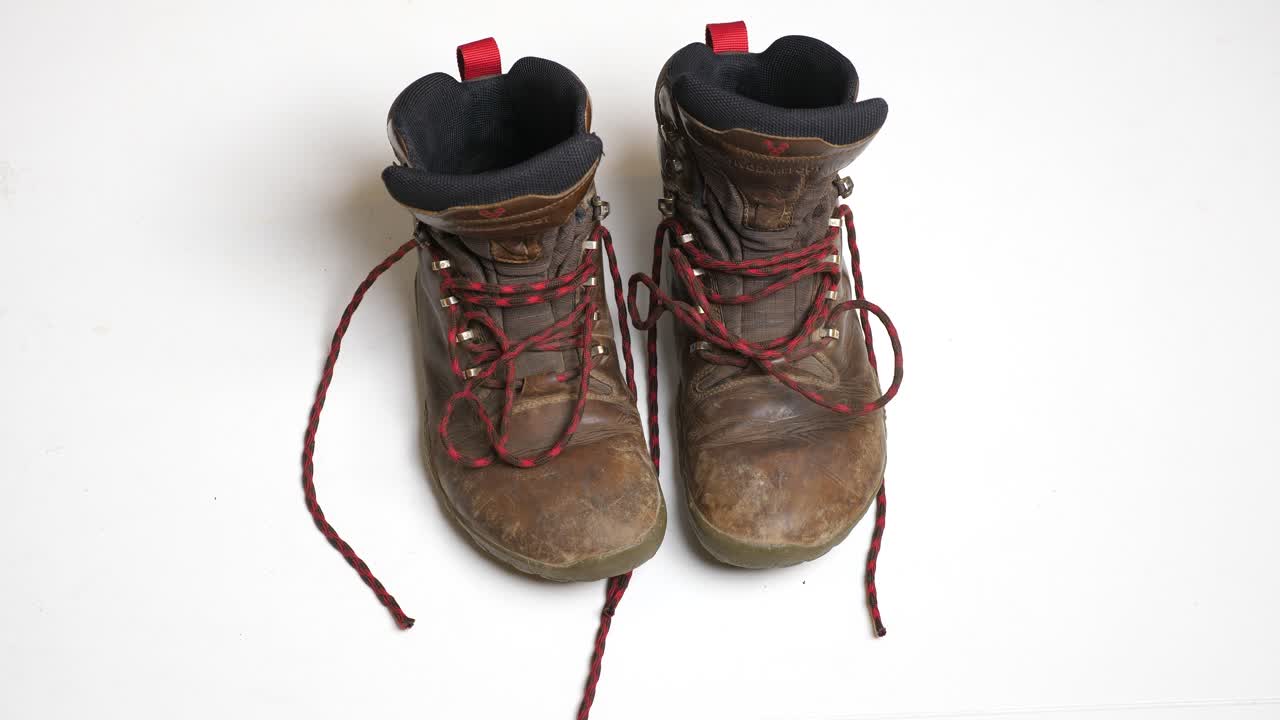 A pair of worn brown hiking boots with red laces