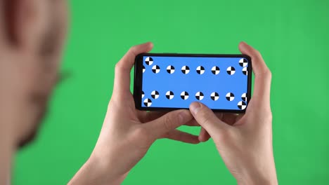 man holds smartphone in horizontal orientation with alpha compositing on display and swipes left