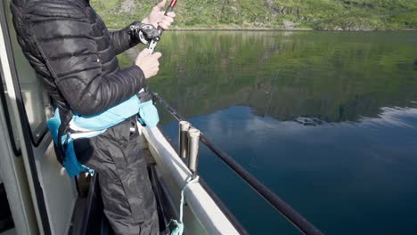 hombre enrollando la caña de pescar en el río de noruega