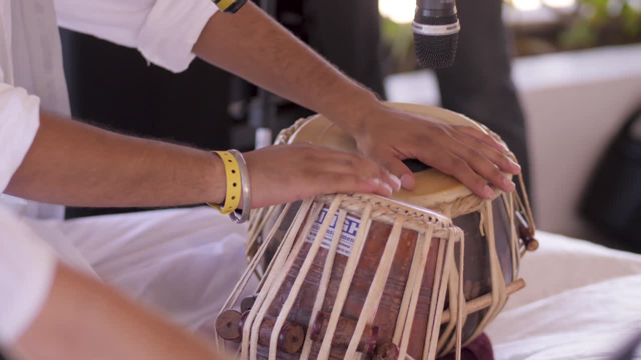 un hombre vestido de blanco toca un par de tambores de "tabla"