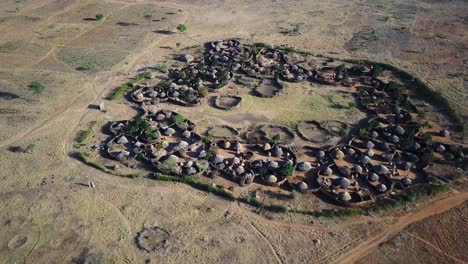 aerial view of drone approaching a village in the karamoja region, also called manyatta or ere, in uganda, during a sunny day