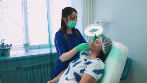 beautician-cleans-woman-forehead-preparing-for-procedure