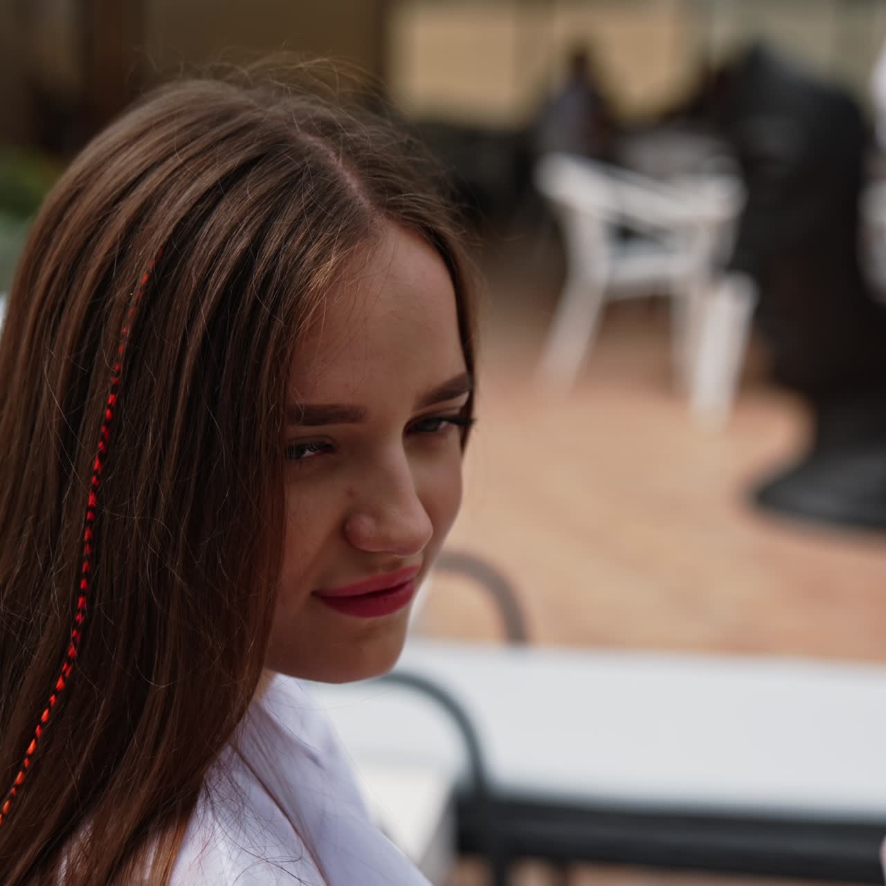 Attractive young girl smiling and taking sip from a wide wineglass. Lady sitting in a deckchair and relaxing with a cocktail. Blurred backdrop