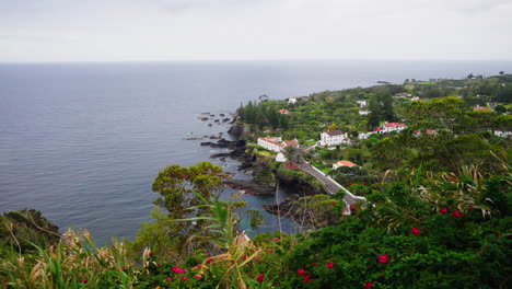 High-view-of-local-town-located-on-top-of-rocky-coastline-surrounded-by-green-lush-vegetation