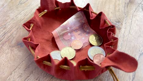 taking money and euro coins out of a small handmade leather pouch close up