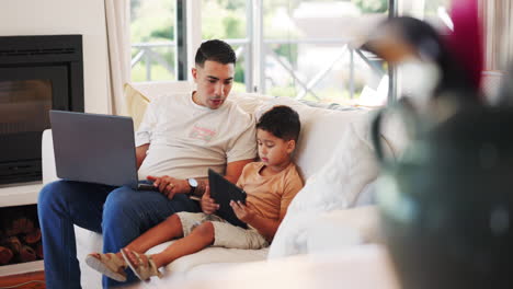 Father,-laptop-and-child-with-tablet-on-a-sofa