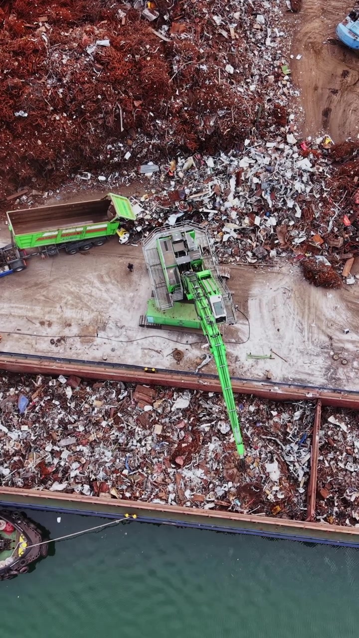 Cargo ship unloads scrap metal near recycling yard in busy port